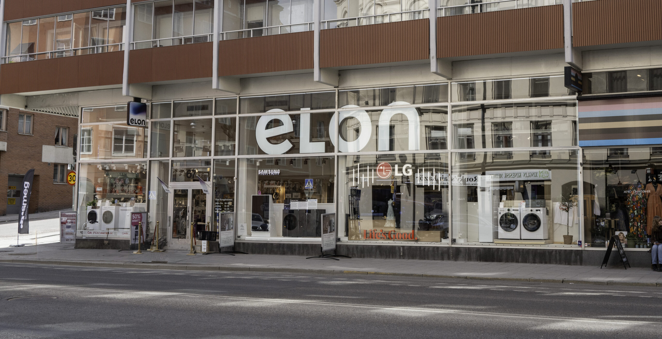 L1002249 Glass-fronted electronics store with a prominent white 'elon' sign across the large storefront window and LG logo visible inside.